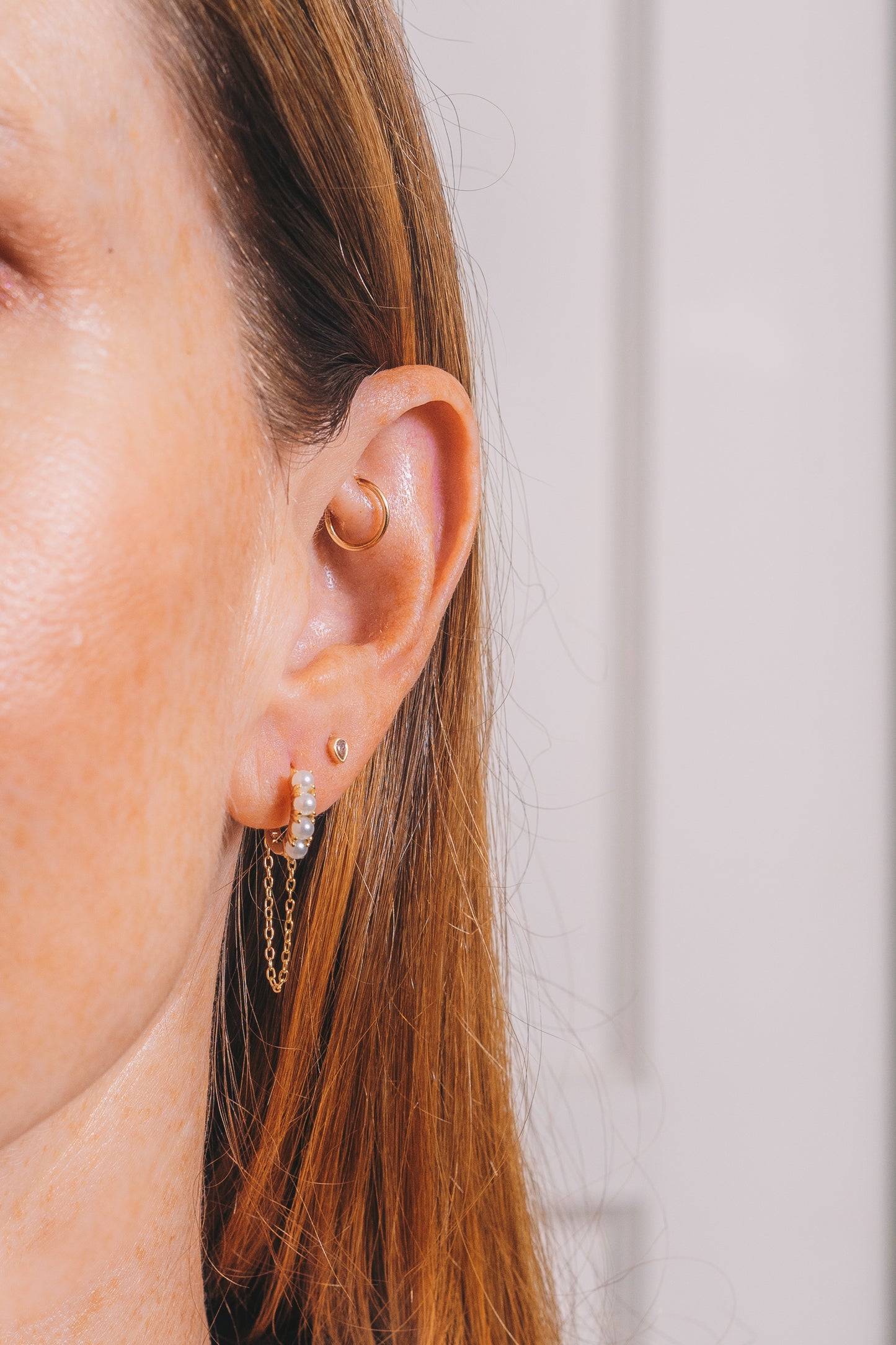 pearl and gold huggie hoops with chain dangles on model closeup