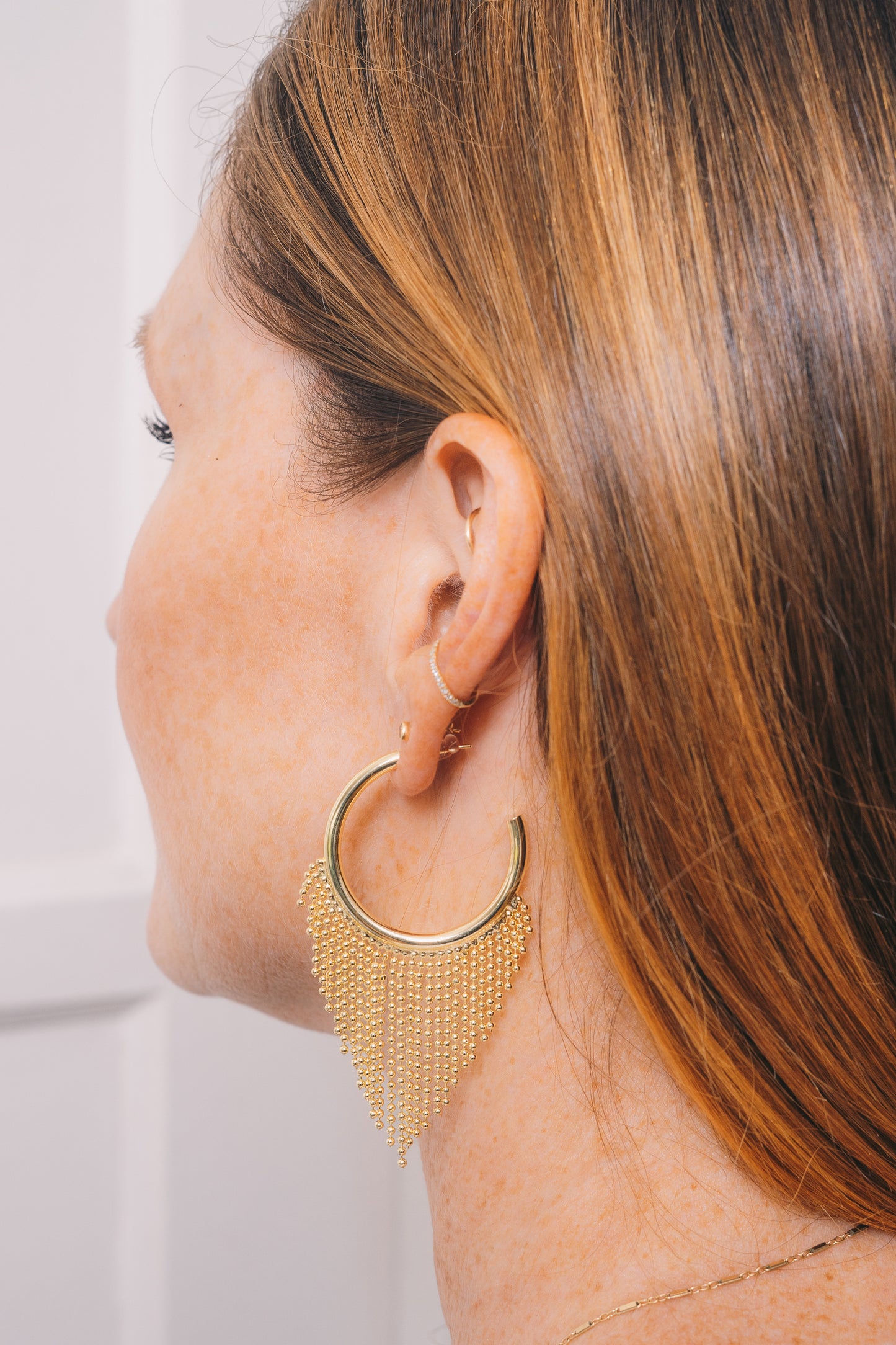 gold hoop chain fringe earrings on model view from side