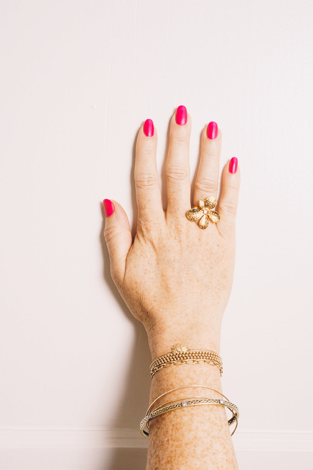 gold flower ring on model hand with stacking bracelets