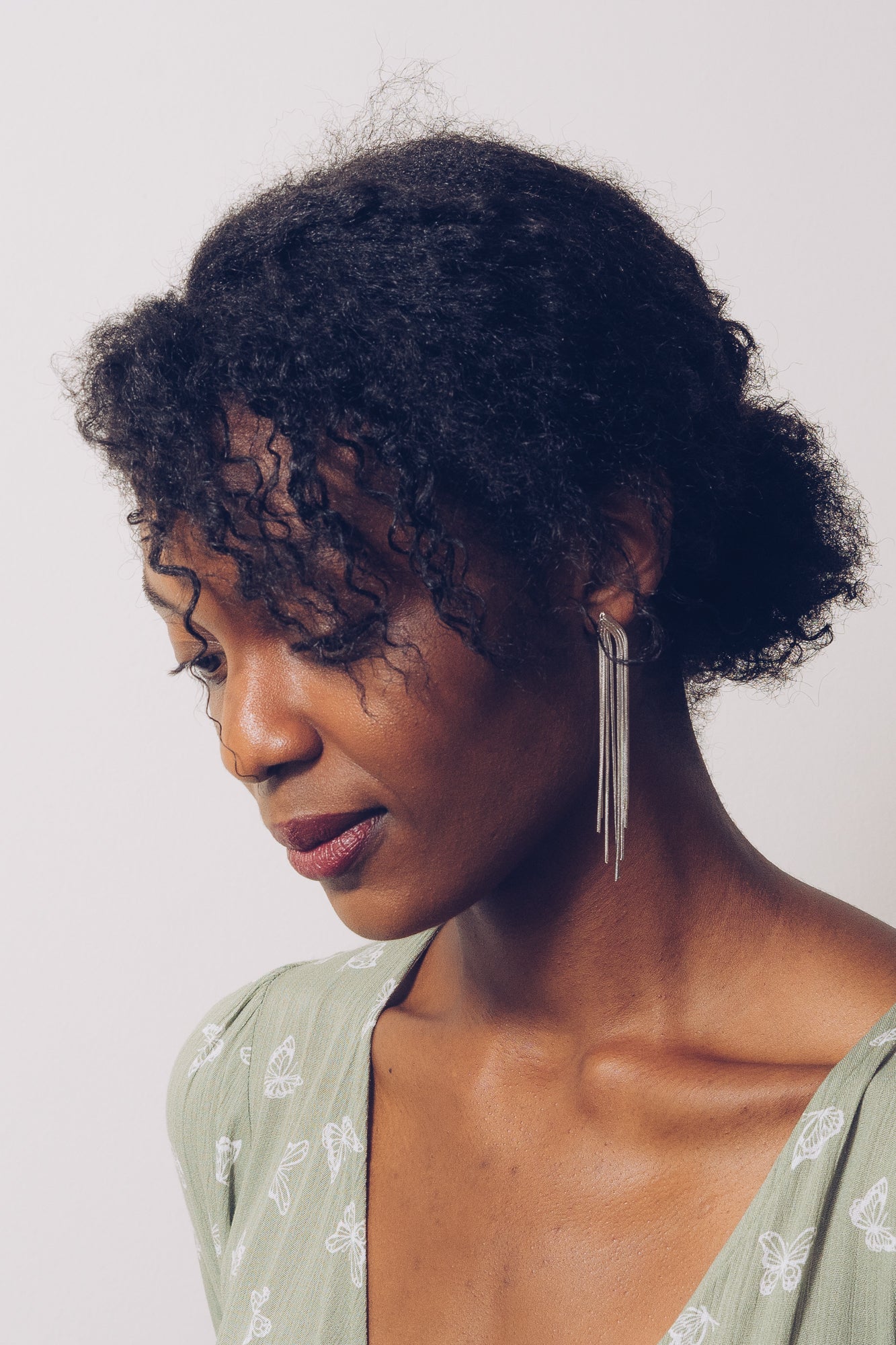 silver chain earrings hanging down model's neck while she looks down