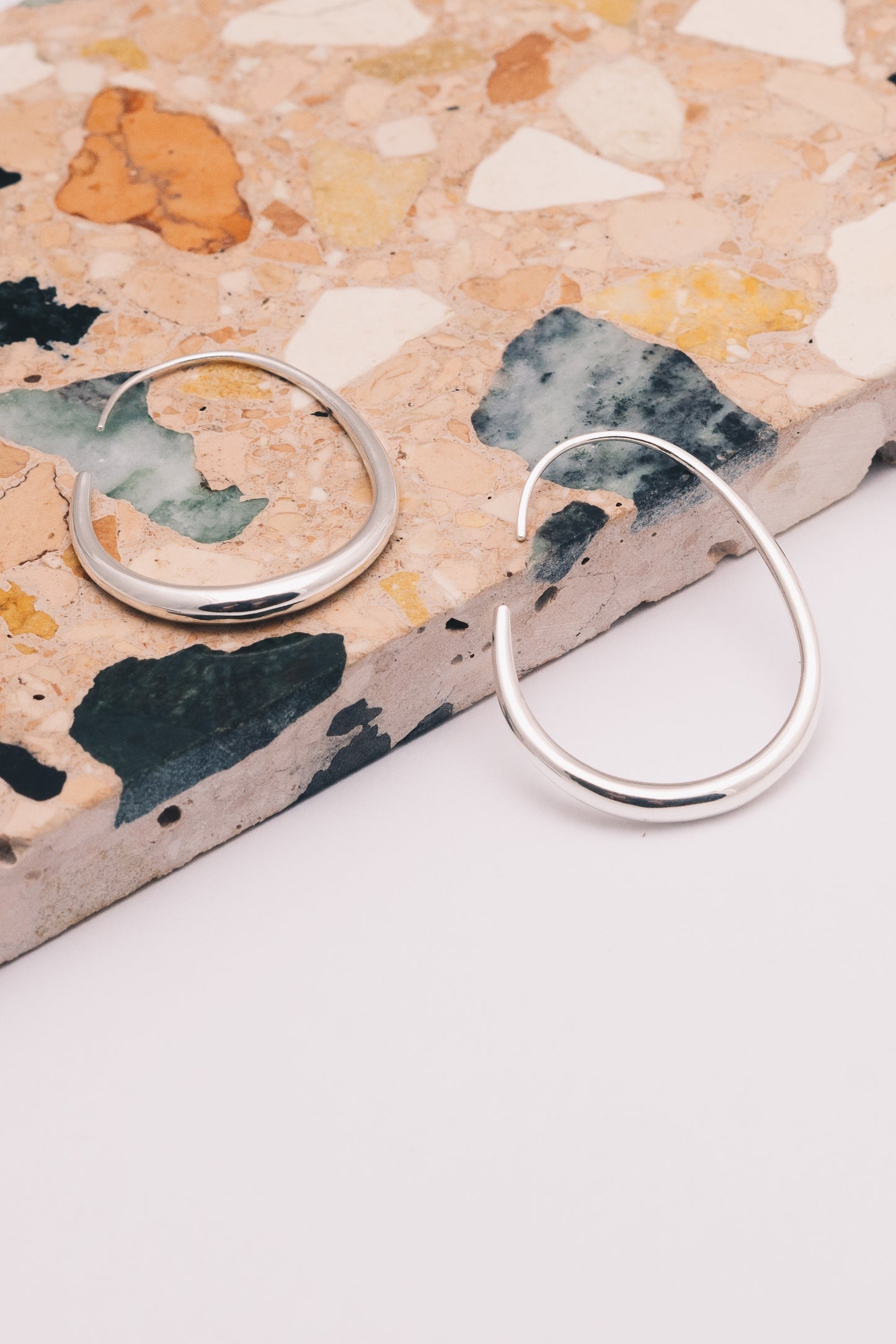 silver threader hoop earrings on patterned marble