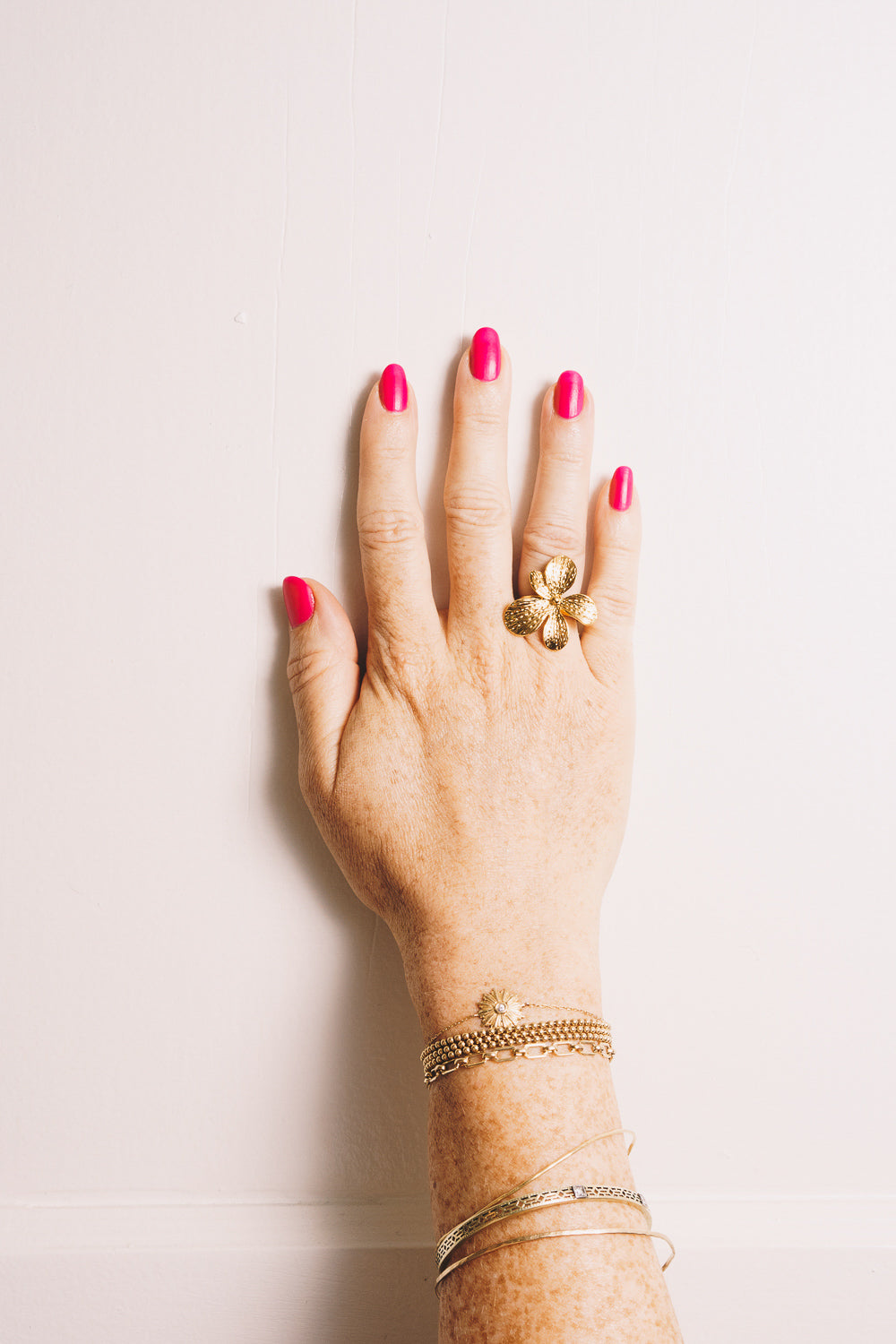 gold flower ring on model hand with stacking bracelets