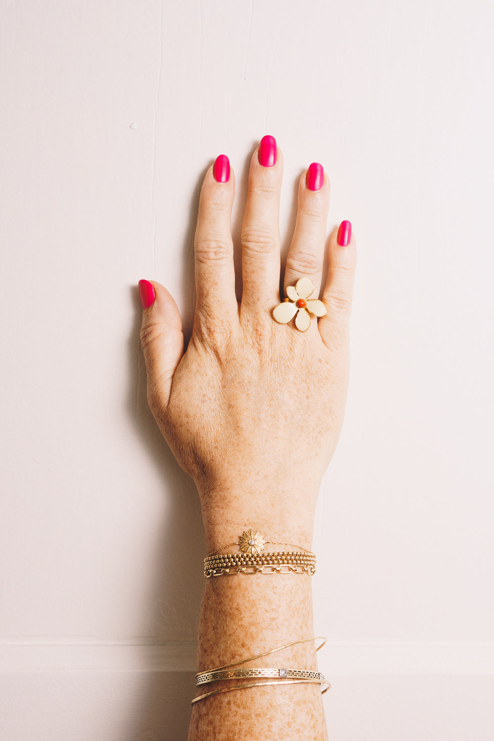 gold enamel flower ring on model hand with stacking bracelets