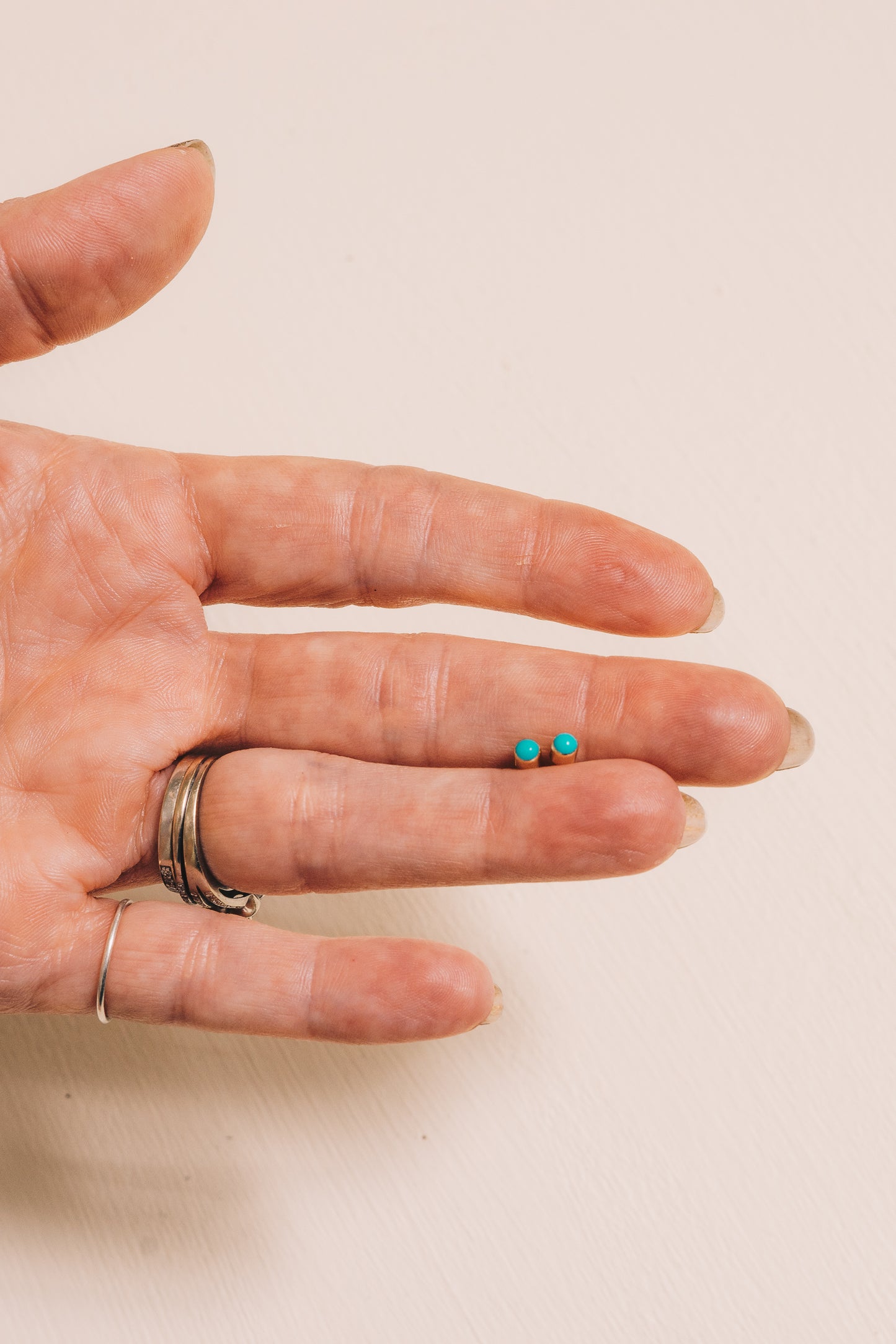 tiny gold turquoise bezel set studs in between fingers