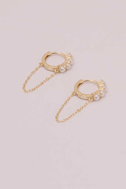 pearl and gold huggie hoop earrings with chain dangles on white background