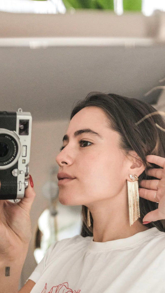 gold chain fringe earrings on model with camera in hand