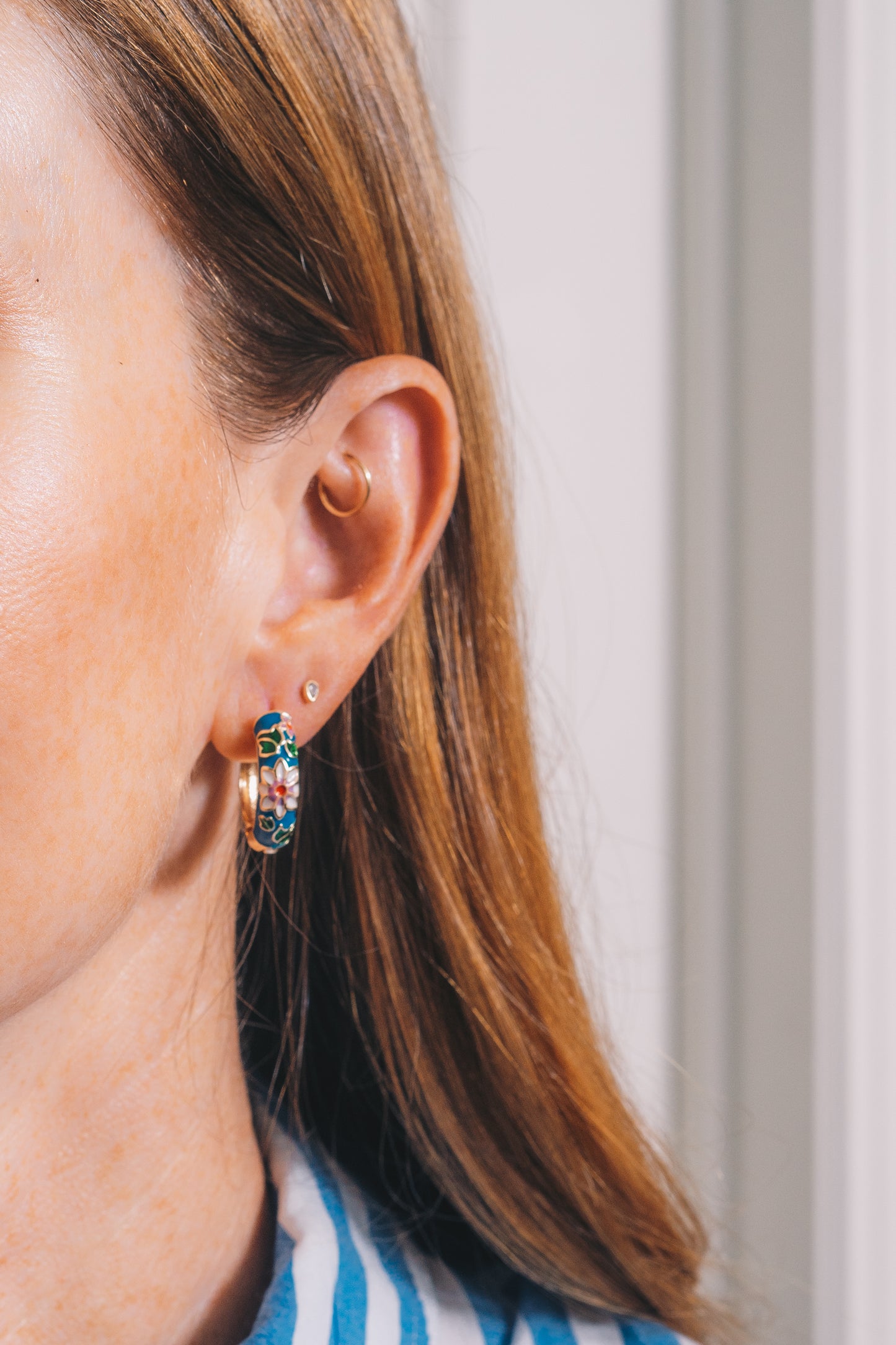 blue cloisonné huggie hoop earrings on red haired model with second piercing and rook piercing