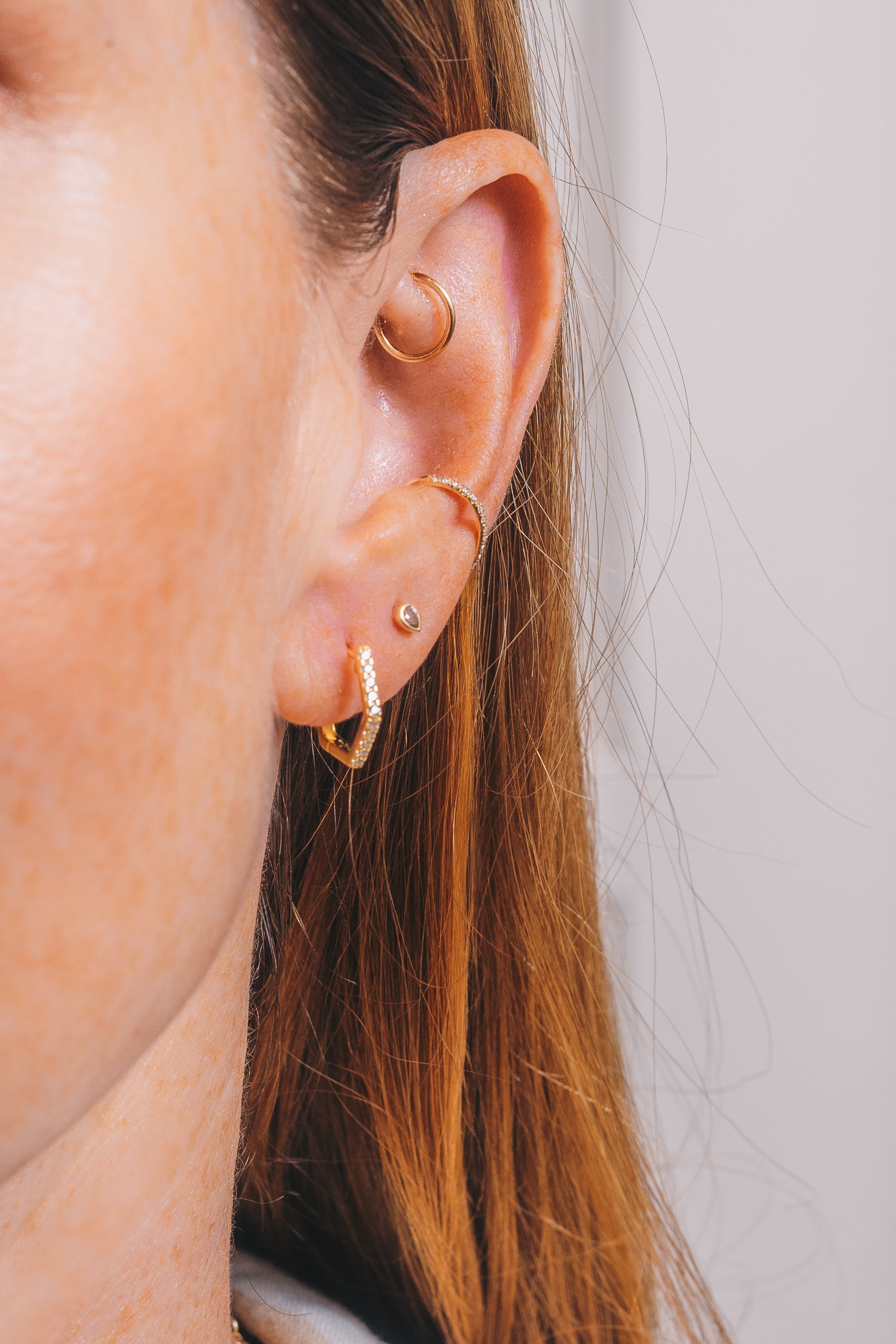 gold hexagon huggie hoops on model closeup