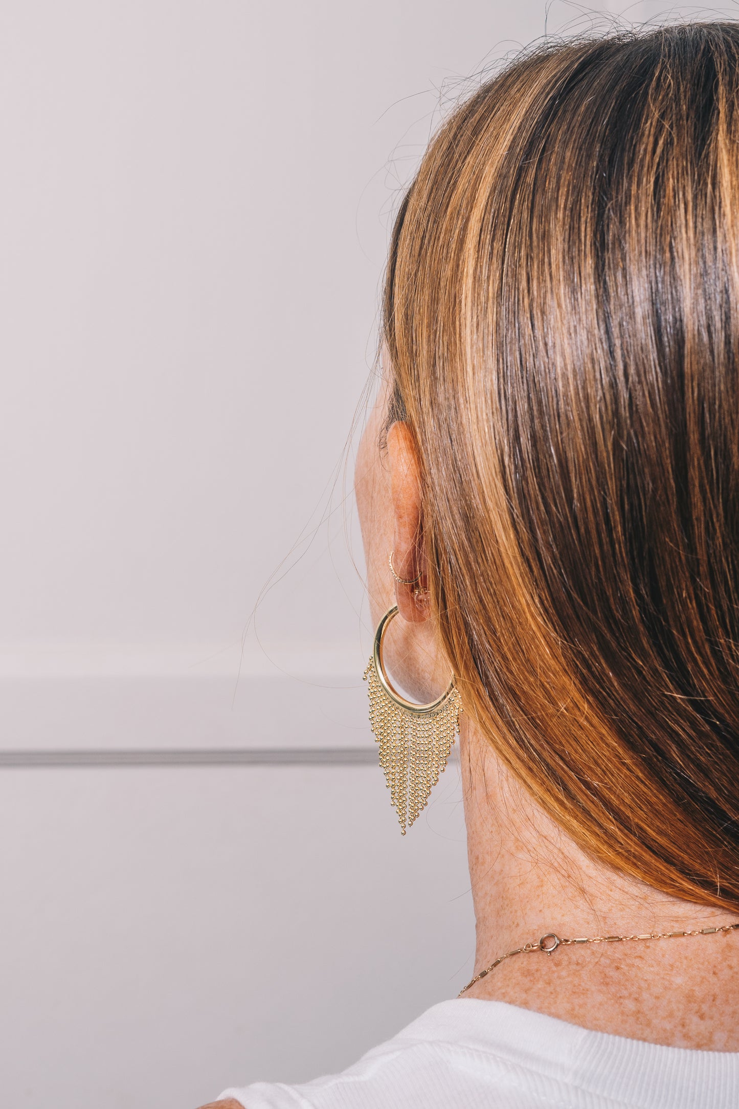 gold hoop chain fringe earrings on model view from over the shoulder