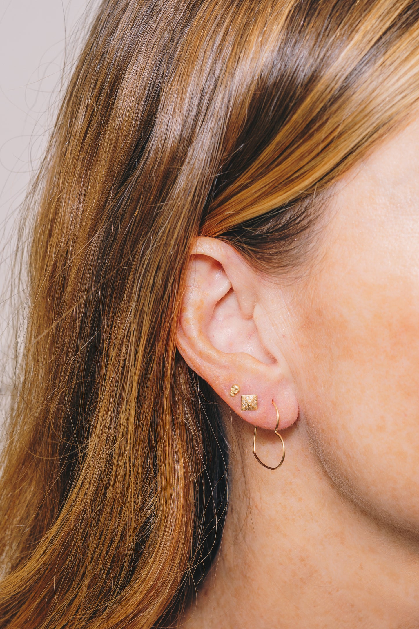 small gold wire heart hoop earrings on model side view