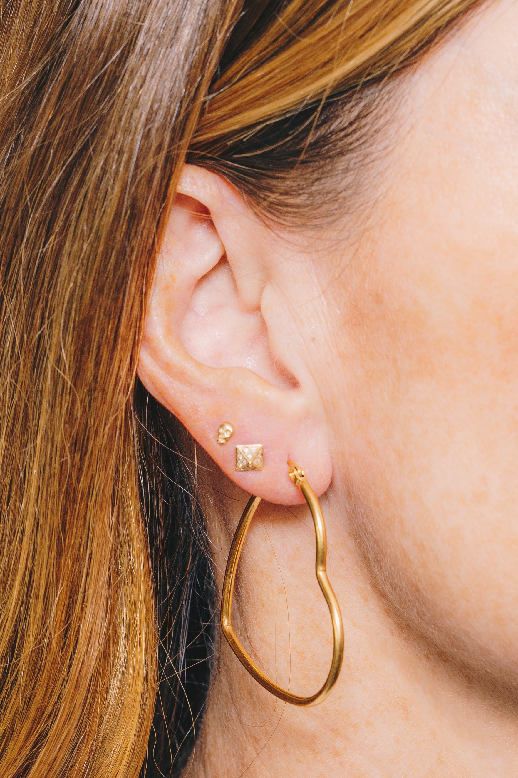 heart hoop earrings on model closeup with pyramid stud and skull studs