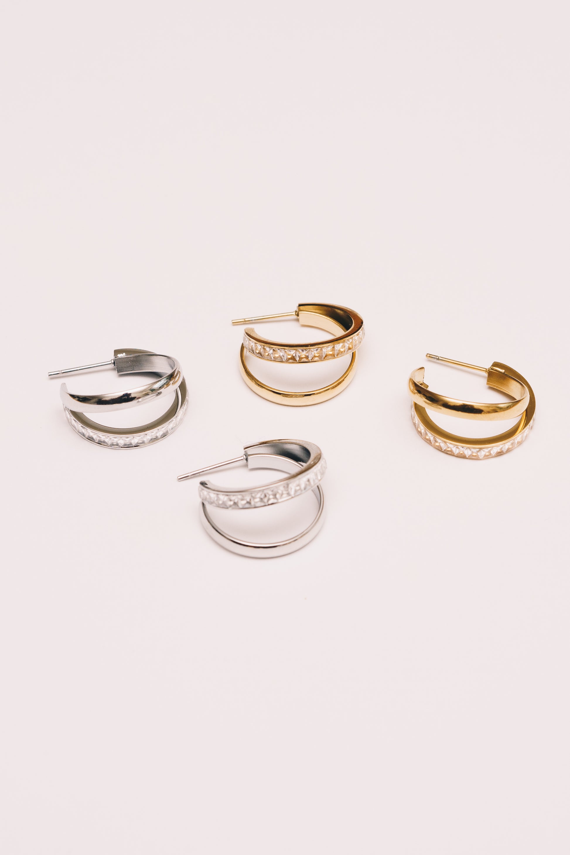 interlocking double hoop earrings in yellow gold and white gold plating on white background
