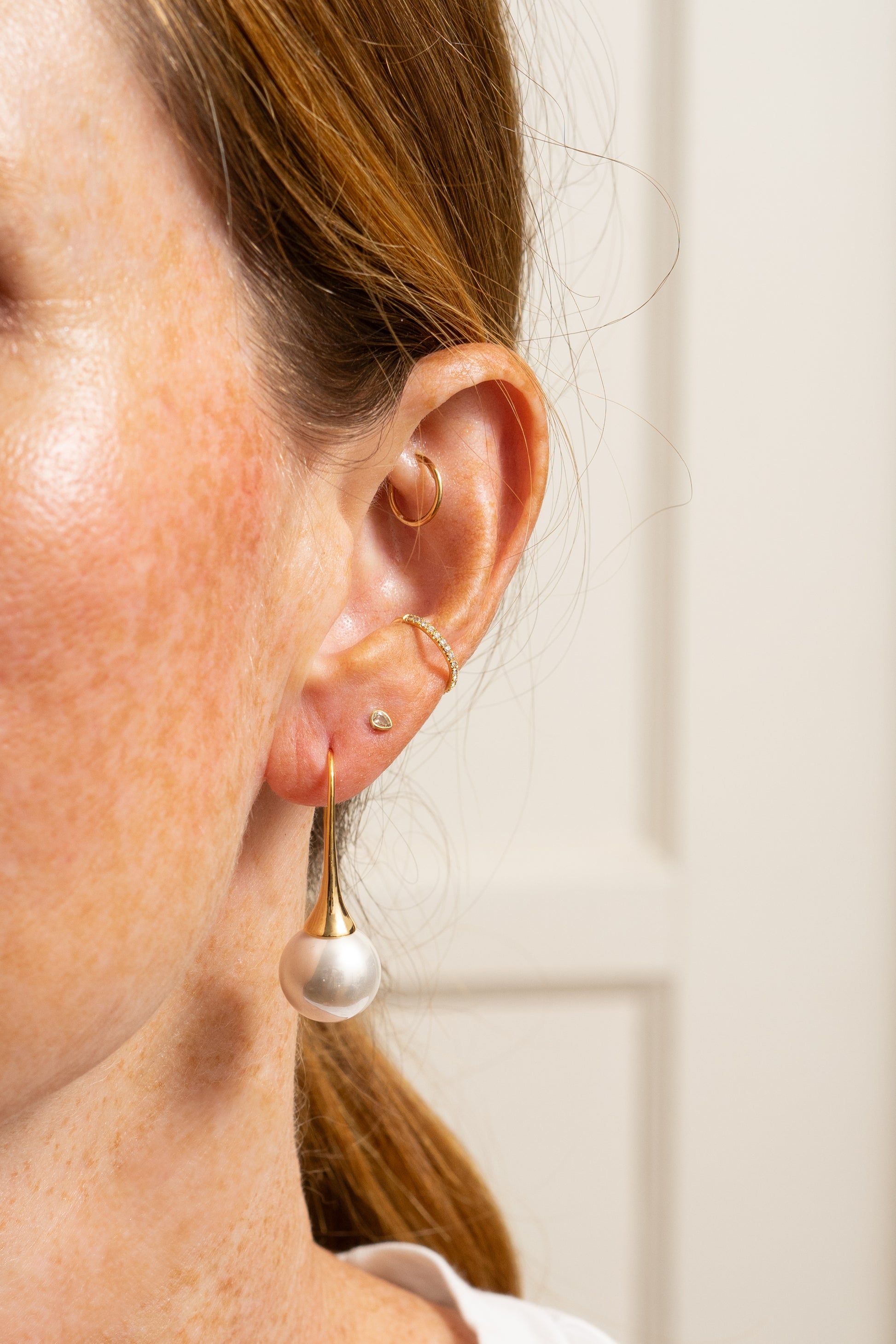 trendy pearl earrings on model with elongated gold earwires