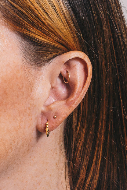 gold spike huggie hoop closeup on ear