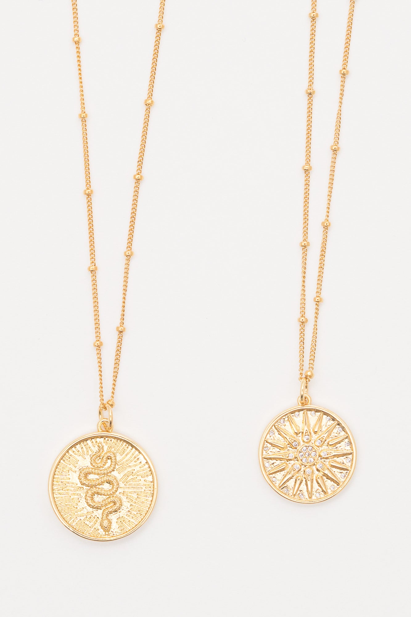 gold layering necklaces with snake charm and starburst charm pendants