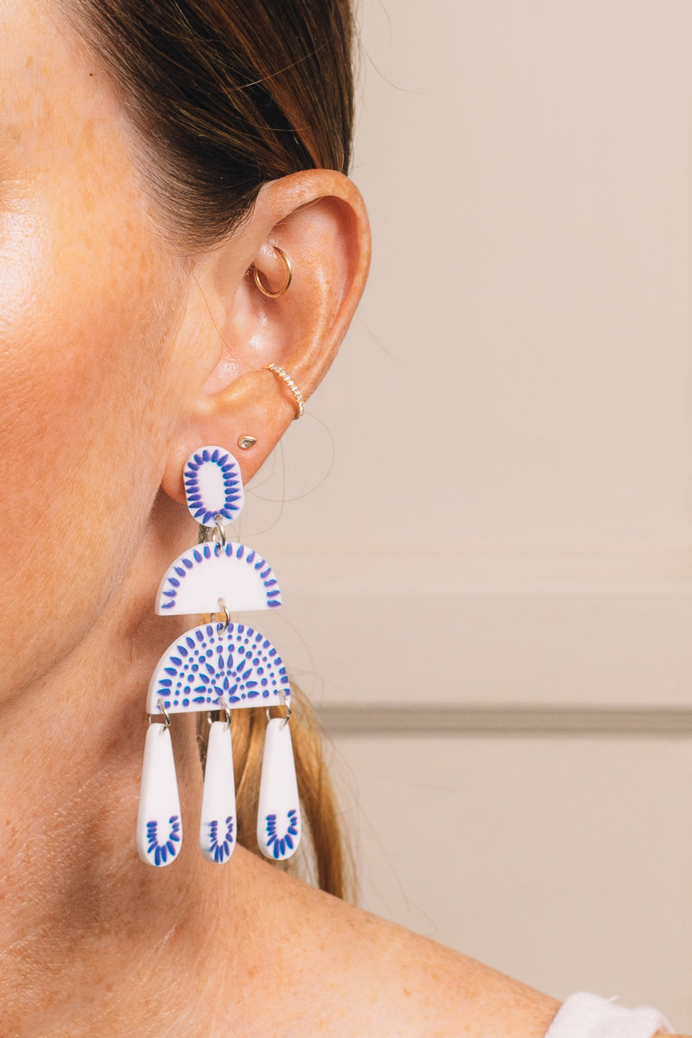 blue and white statement earrings on model