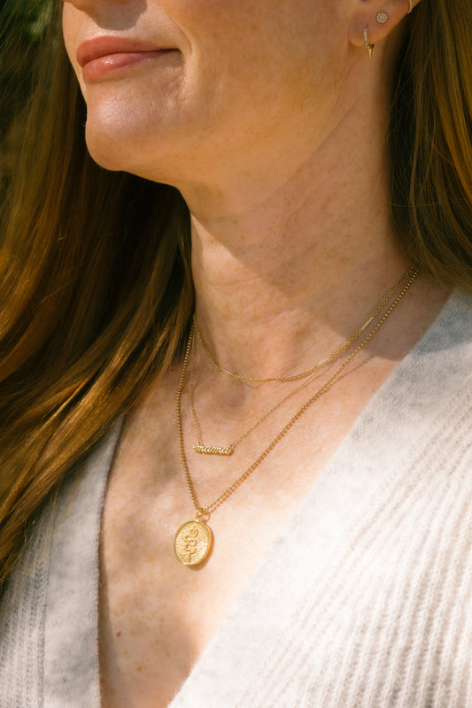 layered gold charm necklaces on model