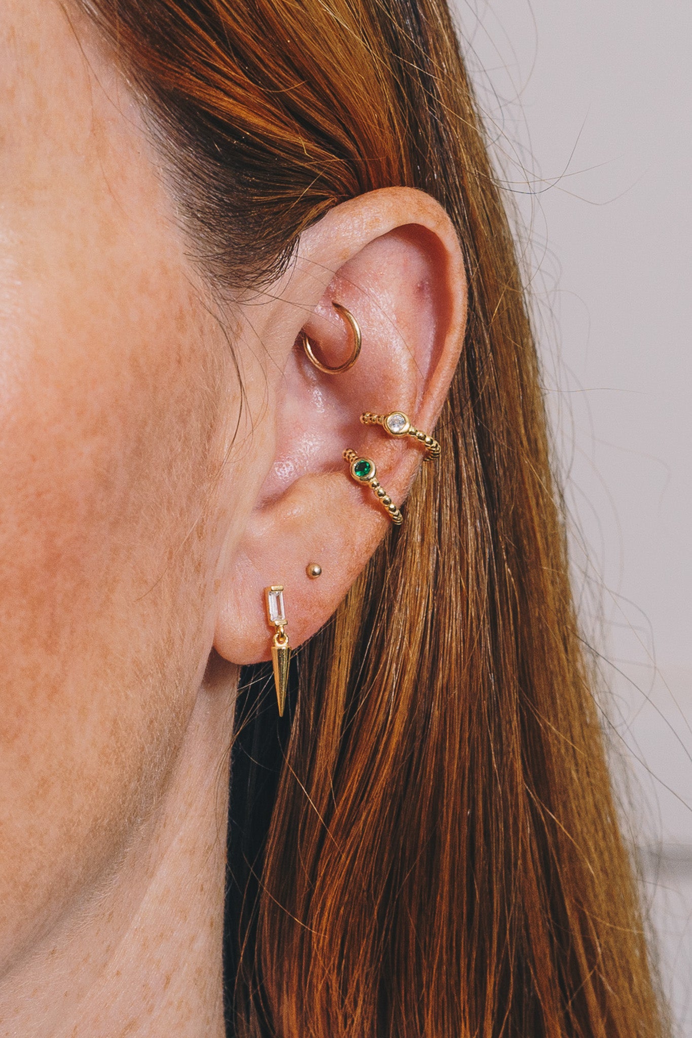 gold and crystal spike stud earrings on model with multiple piercings closeup