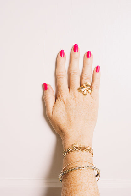 gold flower ring on model hand with stacking bracelets