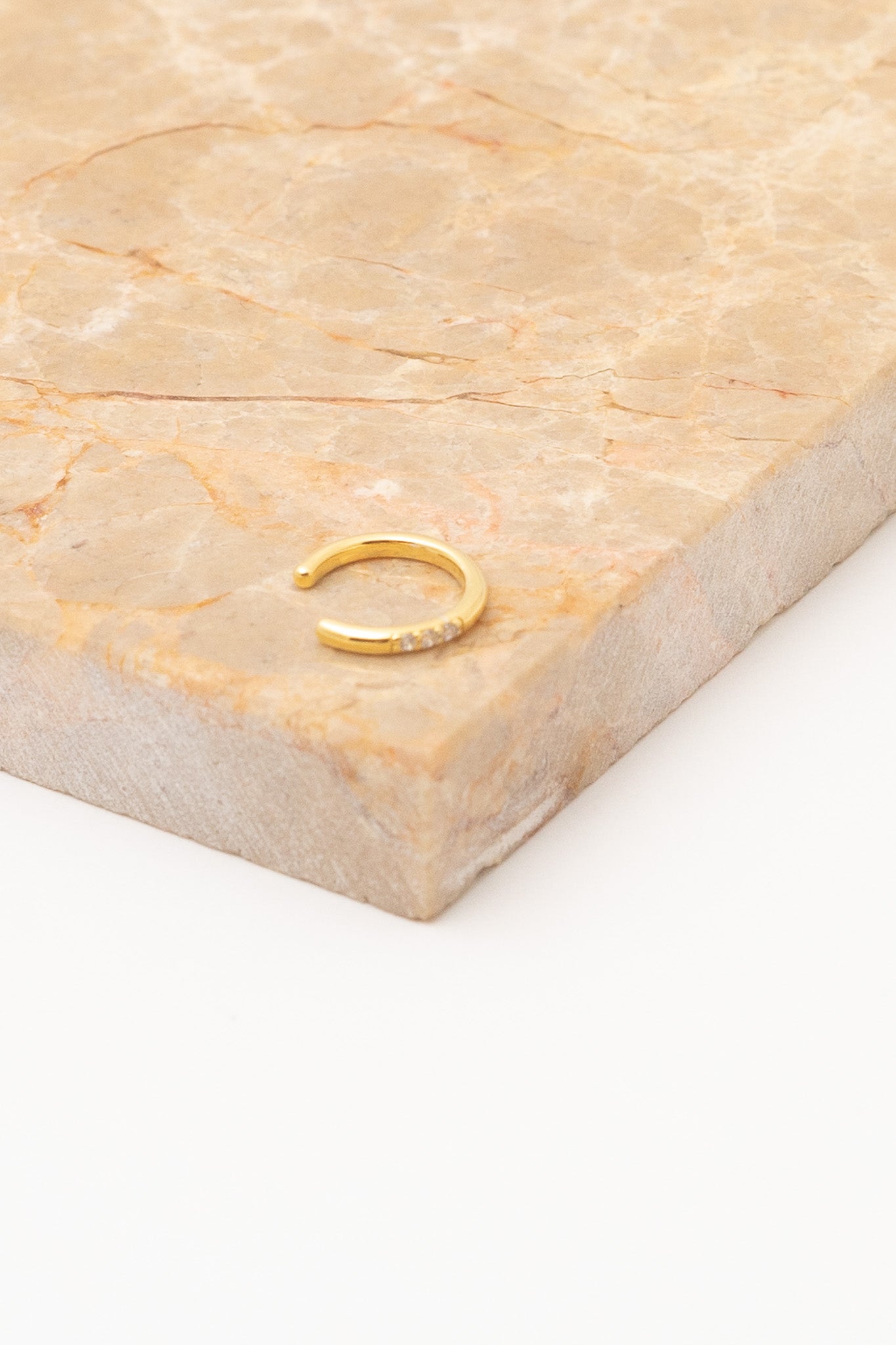 gold thin ear cuff on tan marble background
