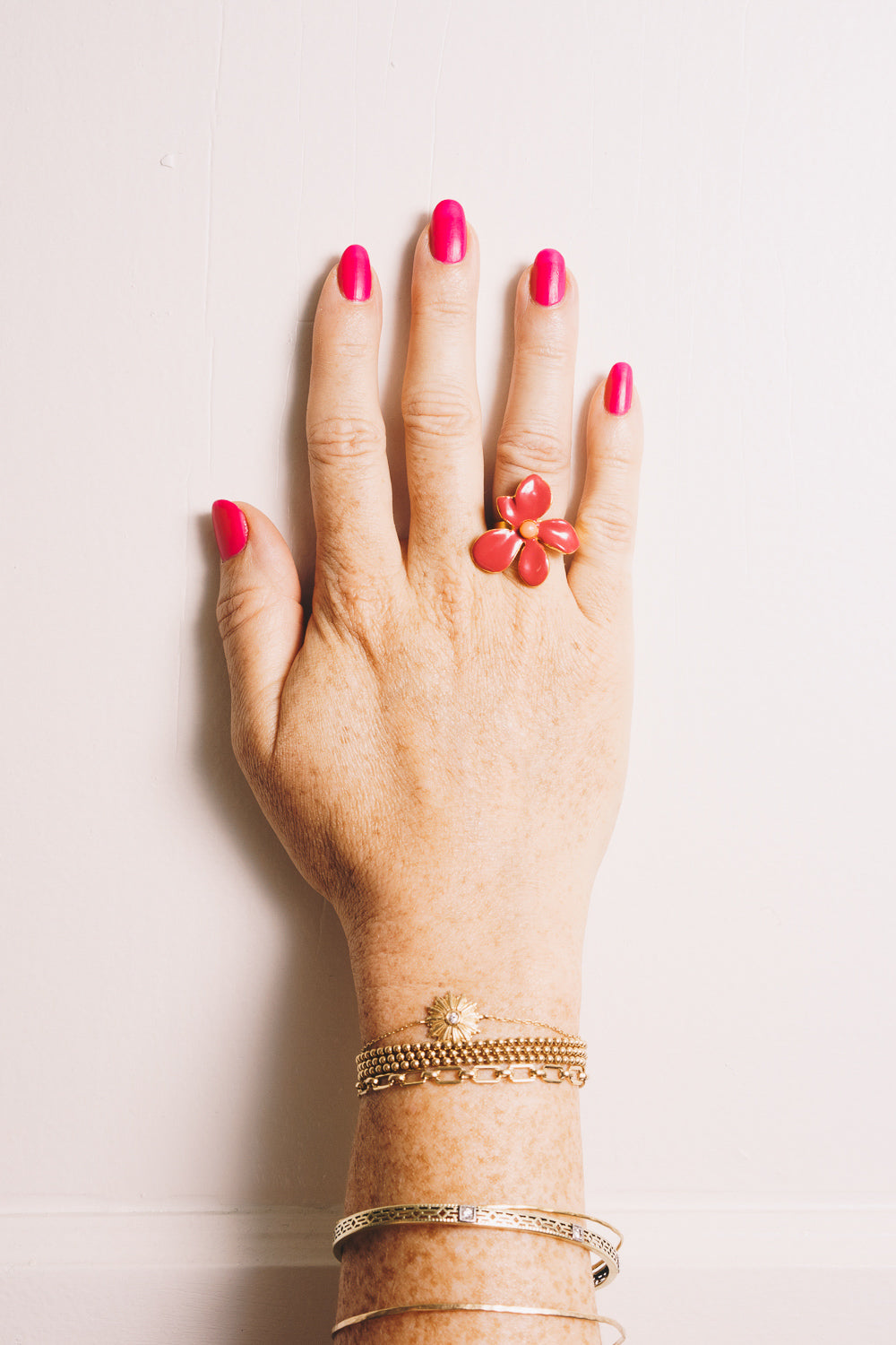 gold enamel flower ring on model hand with stacking bracelets