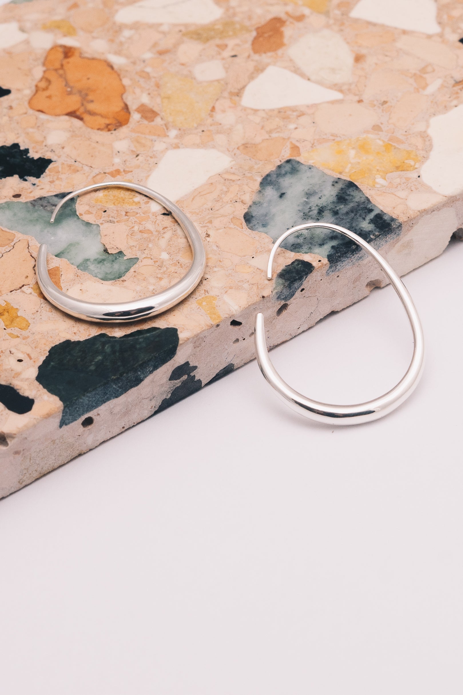 silver threader hoop earrings on patterned marble