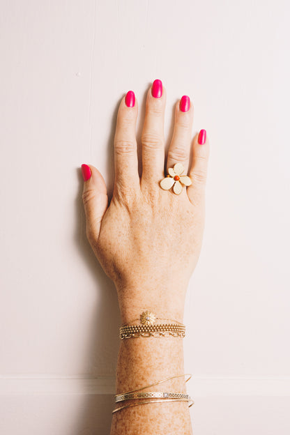 gold enamel flower ring on model hand with stacking bracelets
