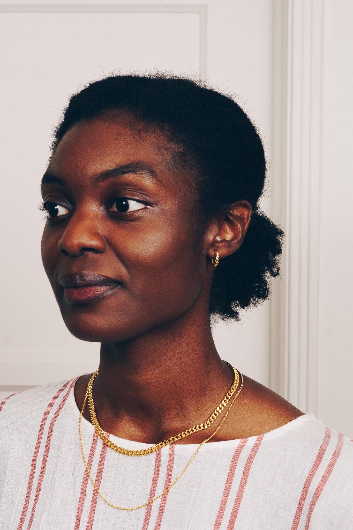 gold baby hoop earrings on model with gold chain necklace