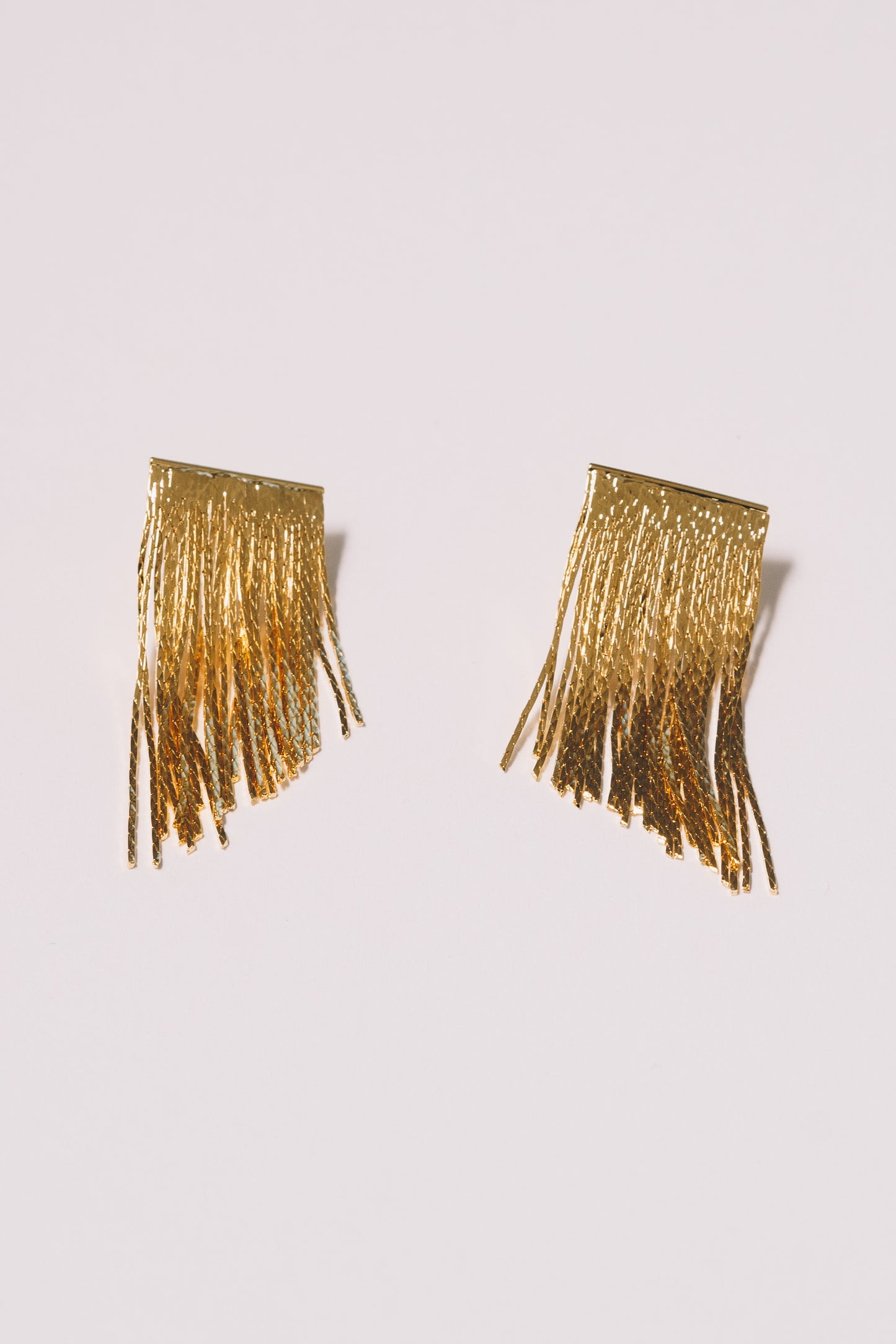 gold fringe stud earrings on white background