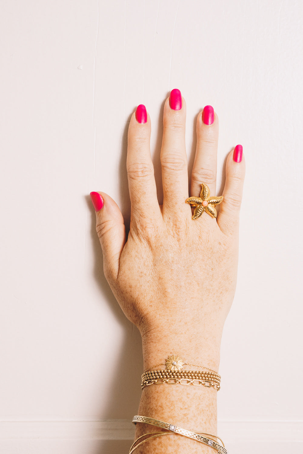 gold starfish ring with coral cabochon on model hand
