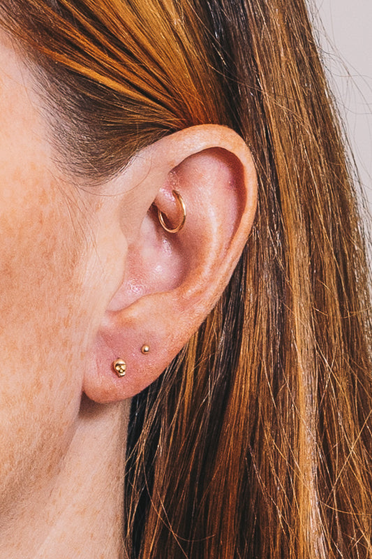 tiny gold skull stud earring with multiple piercing ideas