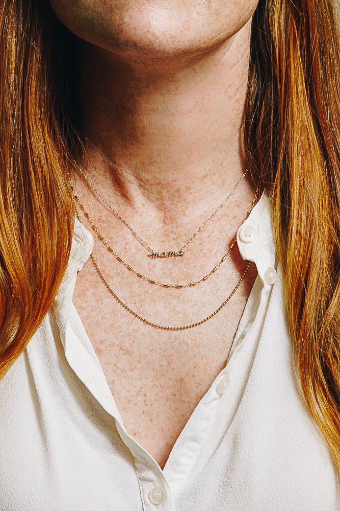 gold mama nameplate necklace with layered necklaces on model