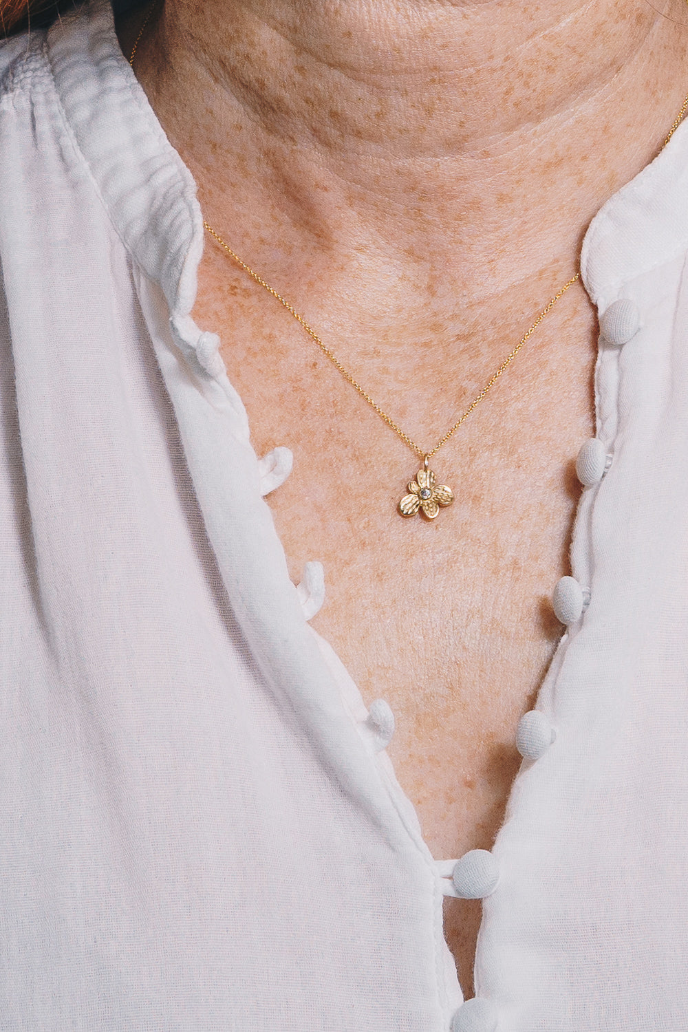 gold and sapphire flower pendant necklace on model