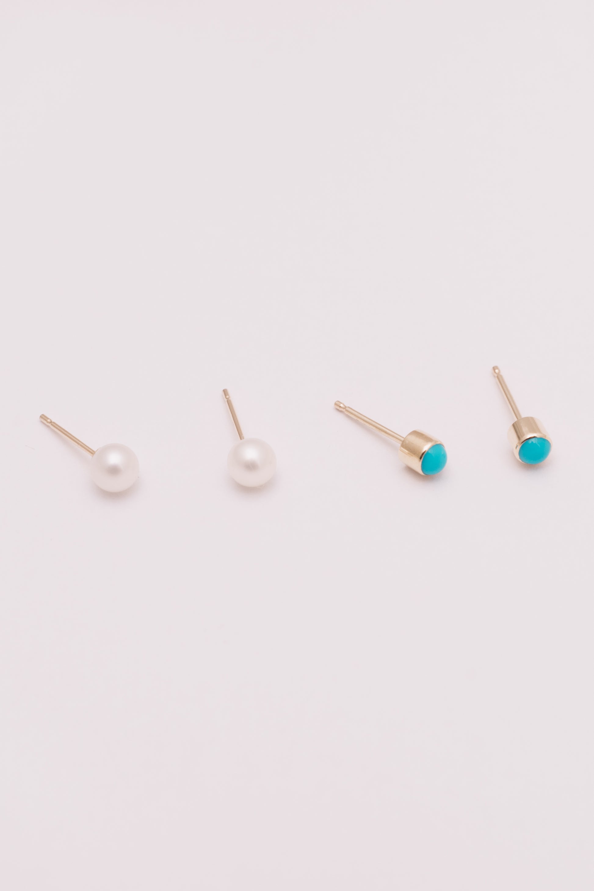 tiny pearl and turquoise stud earrings in gold side by side on white background