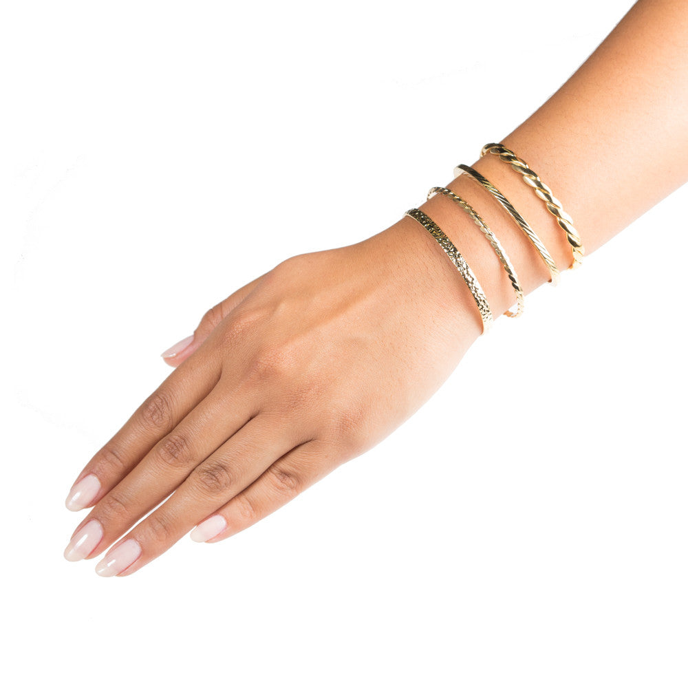 gold cuff bracelets stacked on model arm