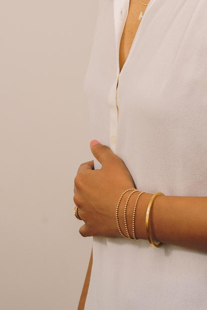 gold beaded bracelets layered with gold cuff bracelet