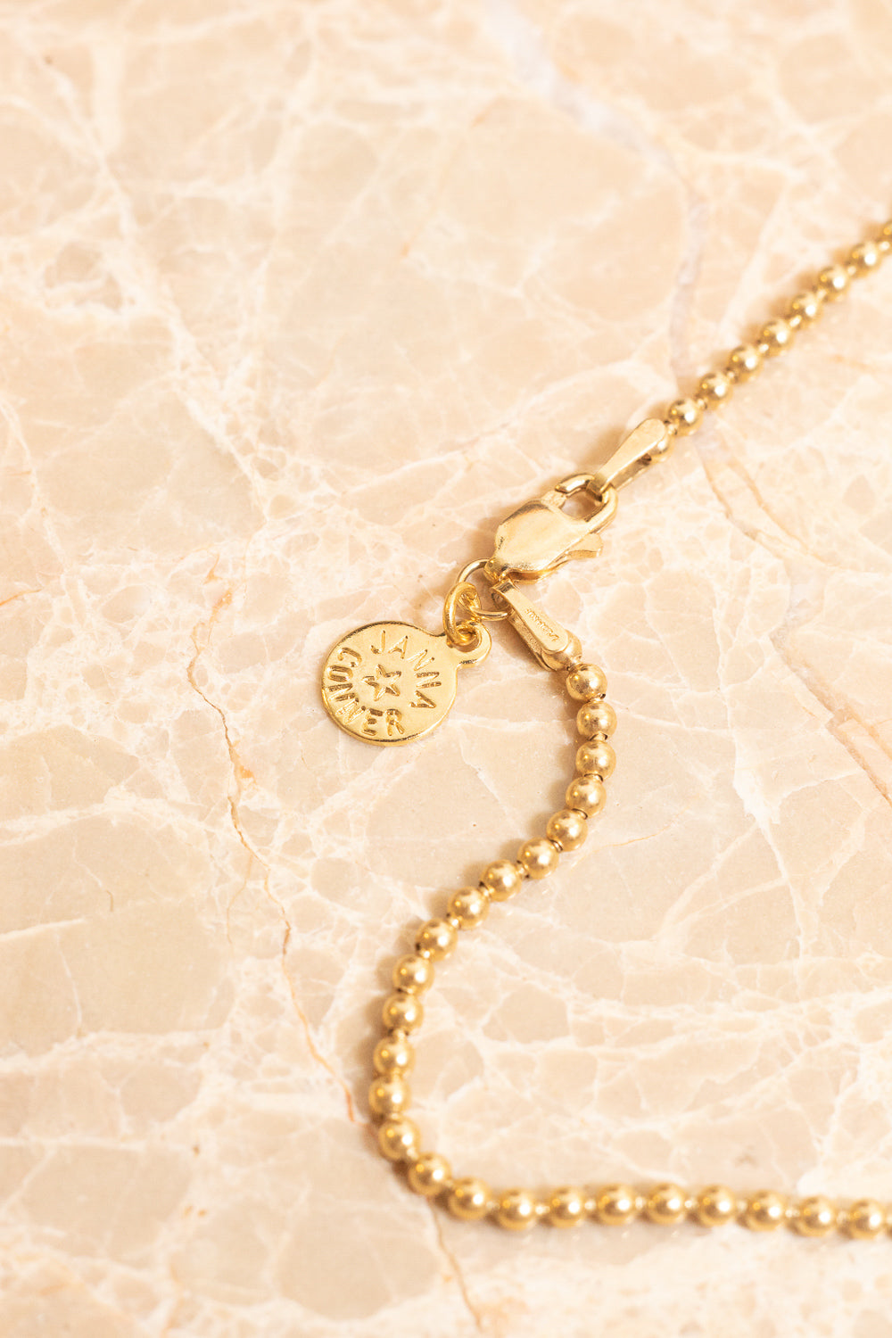 closeup of gold ball chain necklace with nametag