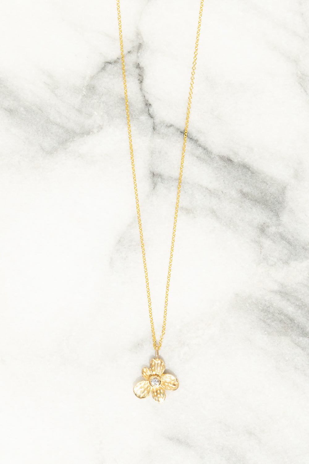 gold flower charm necklace with white sapphire center