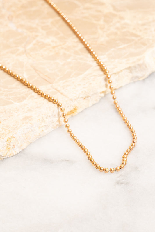 14K Gold filled ball chain necklace laying on marble slab