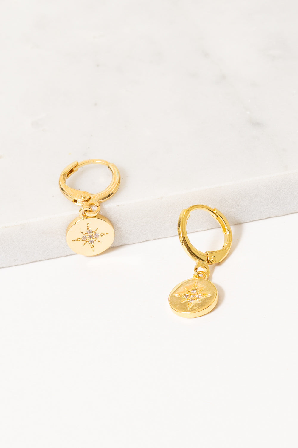 gold huggie hoop earrings with starburst charm dangles by Janna conner