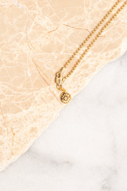 closeup of gold ball chain necklace with nametag
