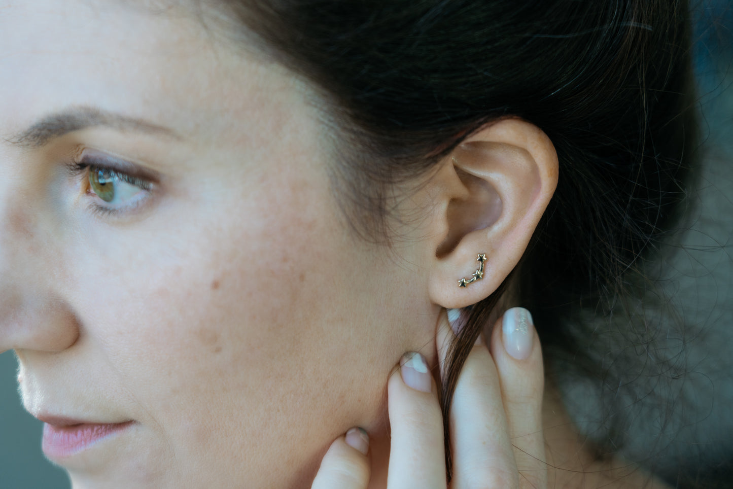 girl touching ear with gold star ear climbers
