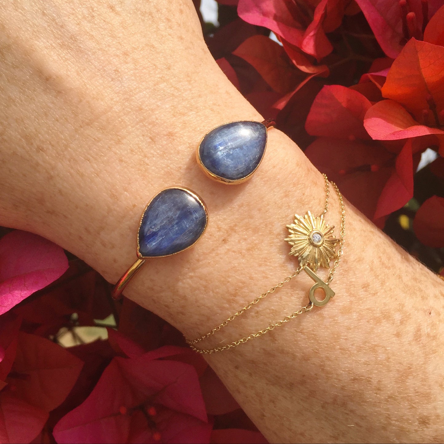 model wrist with gold starburst bracelet, d initial bracelet and kyanite cuff with bougainvillea janna Conner