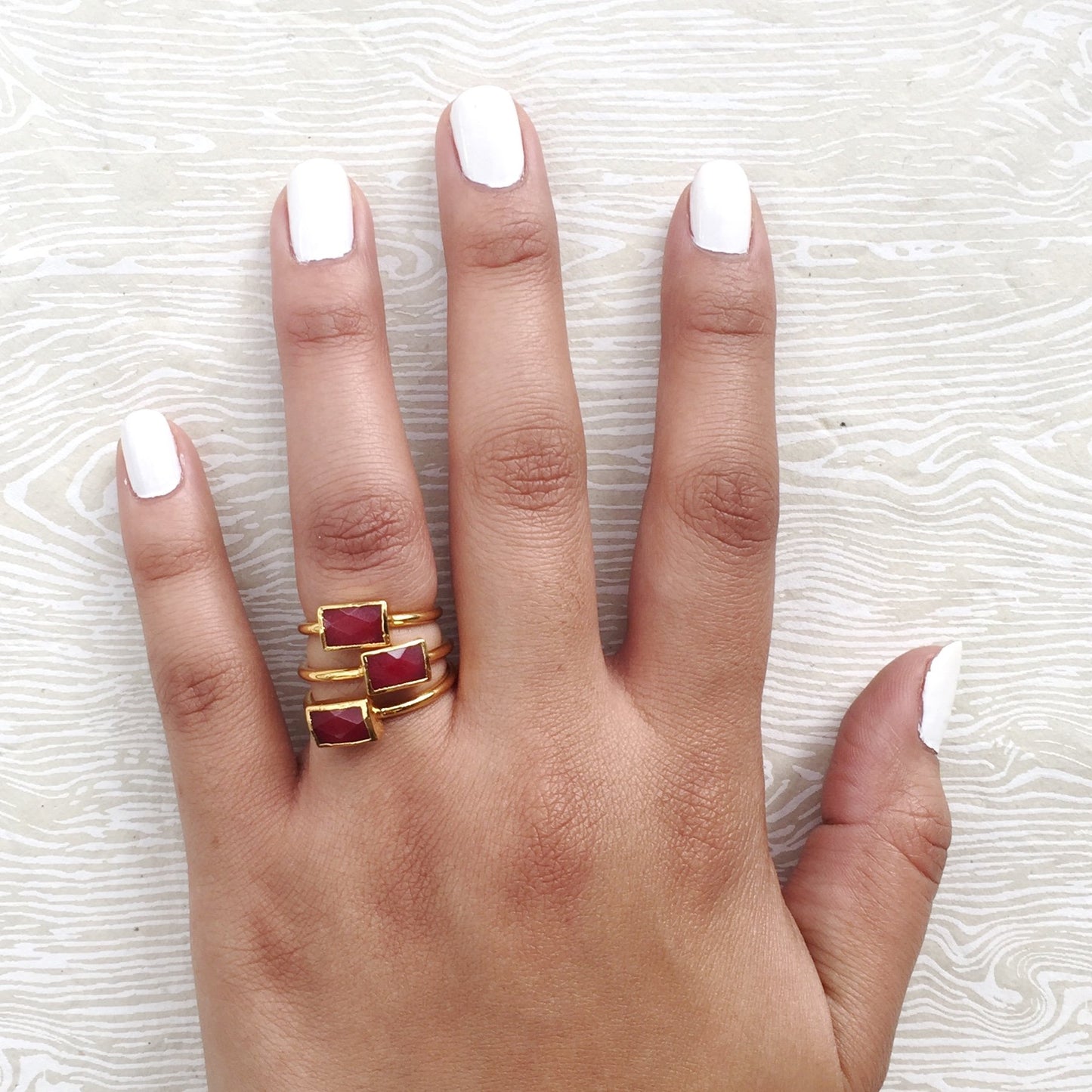 red semi precious stacking rings on hand