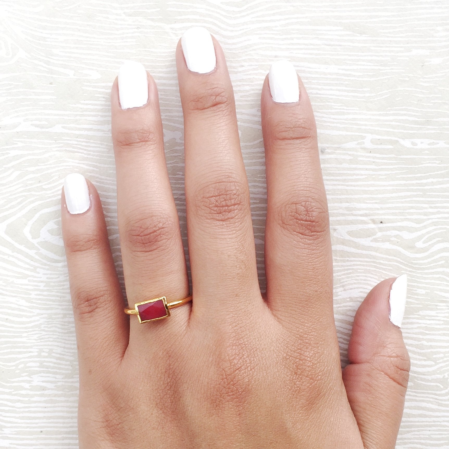 red semi precious stacking rings on hand