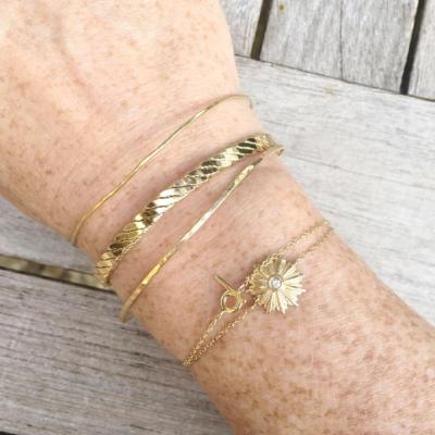 gold stacking bracelets on model arm gold d initial bracelet, diamond  starburst bracelet and gold cuff and bangles by janna conner