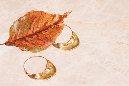 gold sculptural hoop earrings with autumn leaf