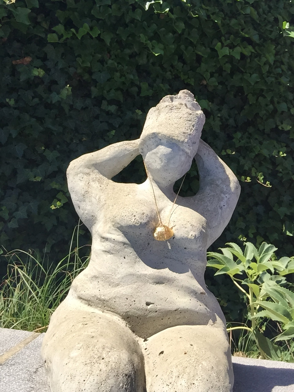 gold seashell charm necklace on statue